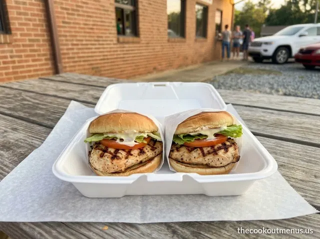 Two char-grilled chicken sandwiches with lettuce, tomato and mayo in a foam tray