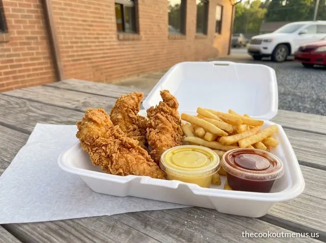 Three crispy chicken strips with fries, honey mustard and BBQ sauce in a foam tray