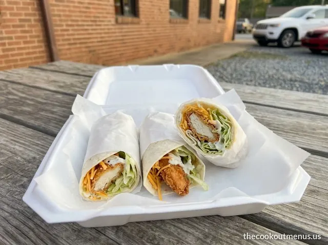 Three small chicken wraps with cheese, lettuce and ranch in a foam tray