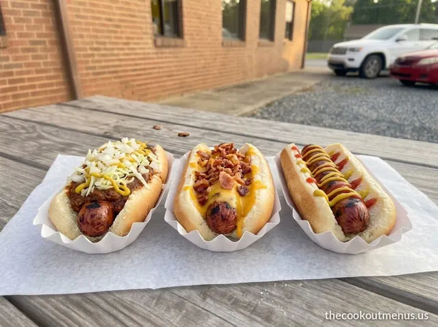 Three char-grilled hot dogs from the Cookout menu: chili and slaw, bacon and cheddar, and ketchup and mustard