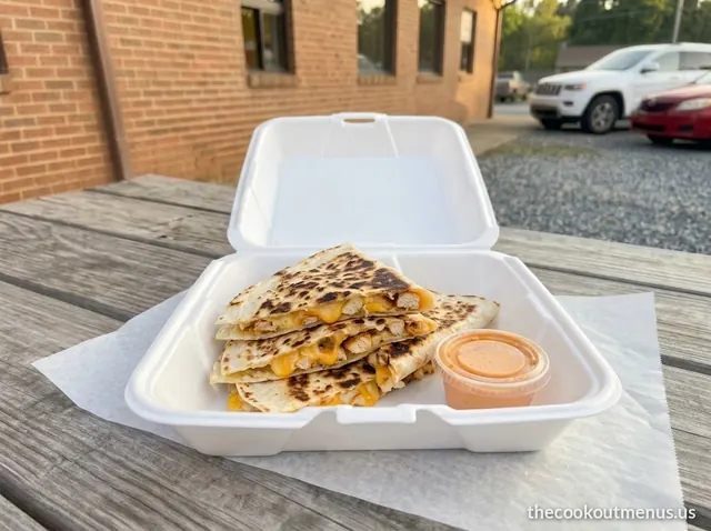 Chicken and cheese quesadilla wedges in a foam tray with a cup of quesadilla sauce