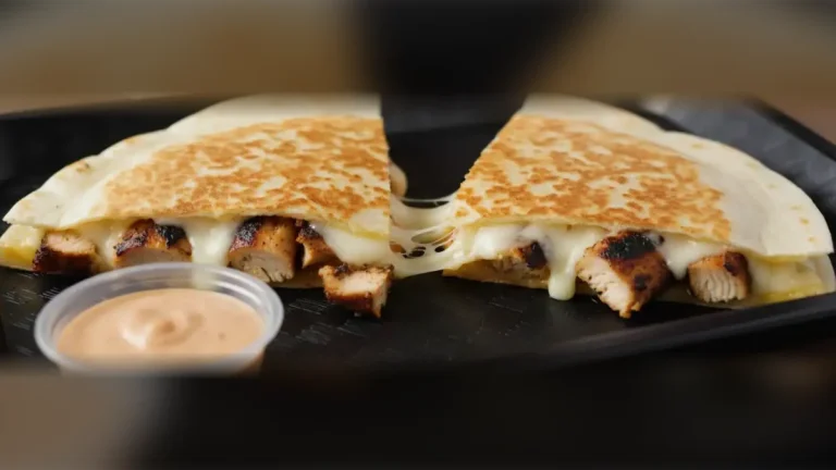 Cookout chicken quesadilla cut in half with melted cheese and a cup of quesadilla sauce