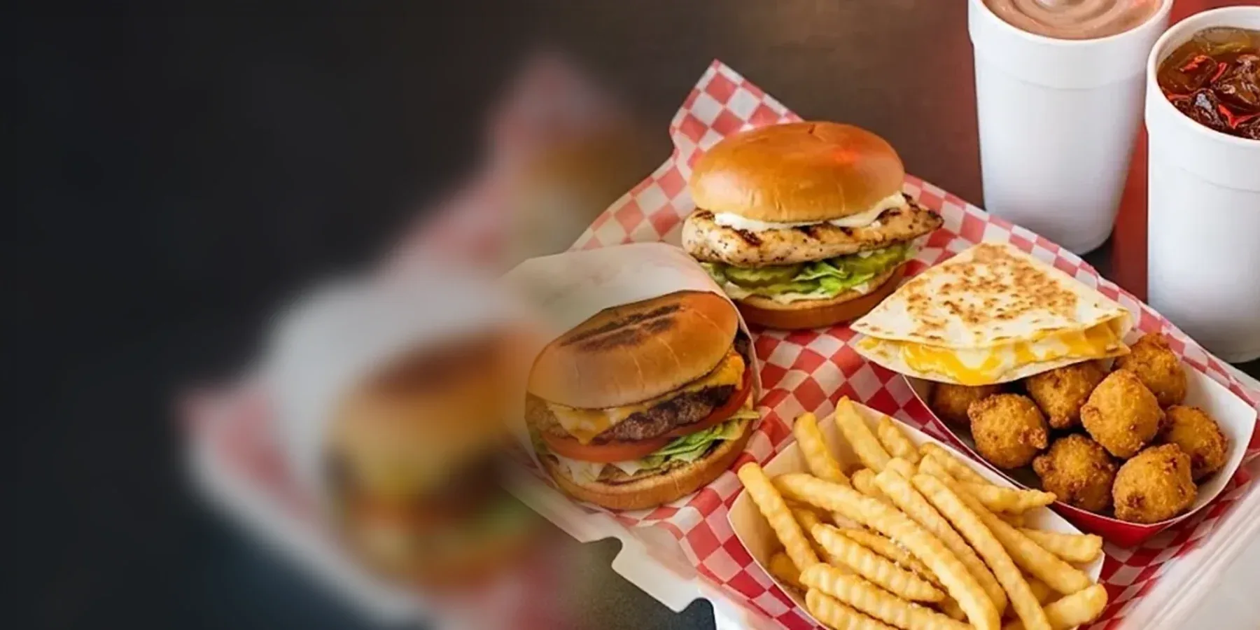 Cook Out style tray meal with a cheeseburger, chicken sandwich, quesadilla, fries, hushpuppies, a milkshake and sweet tea